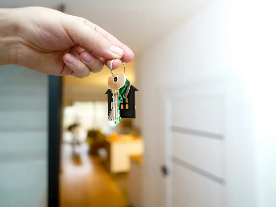 Hand holding house keys in a bright front entrance